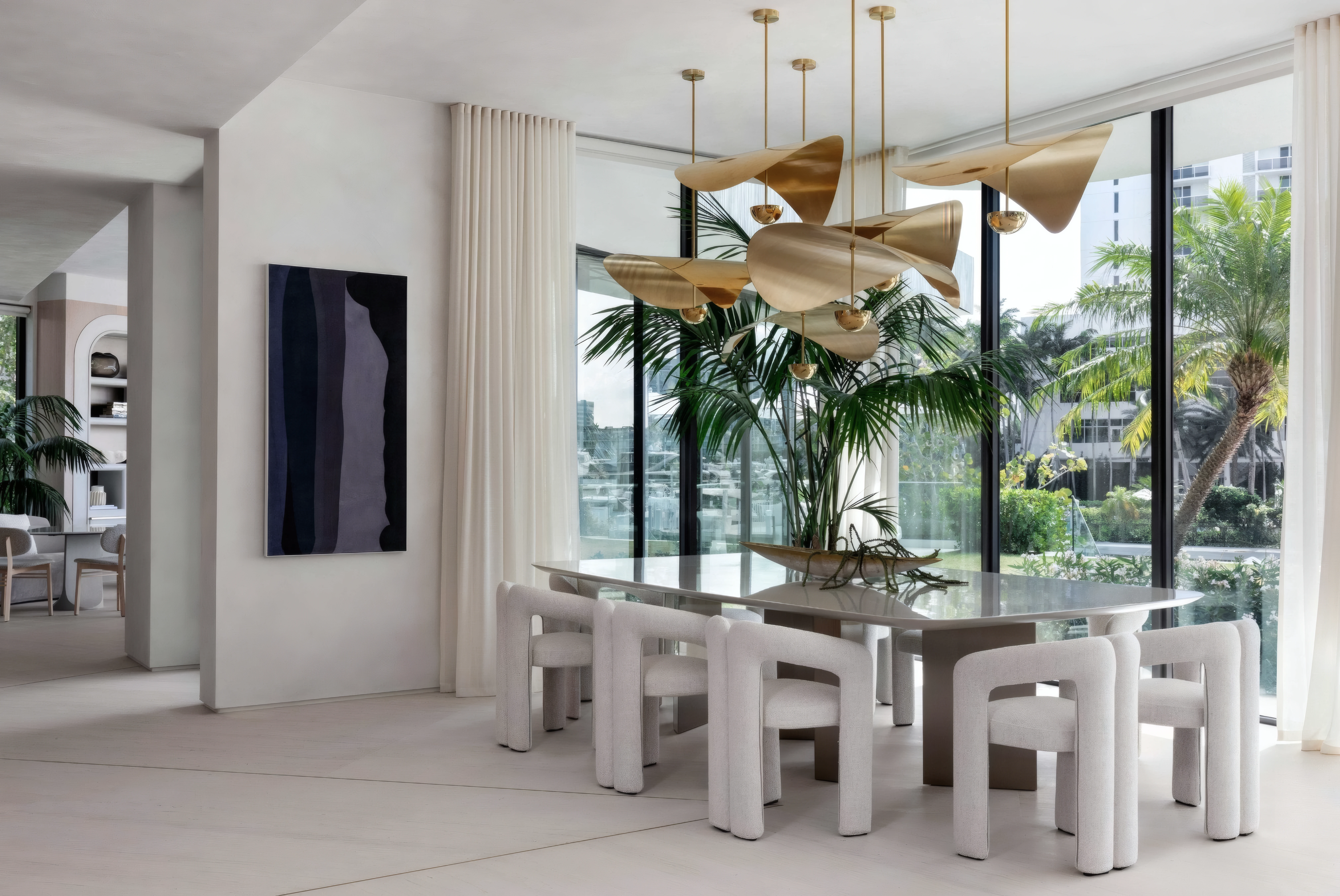 Double-height dining room with a sculptural gold pendant cluster hanging from the high ceiling